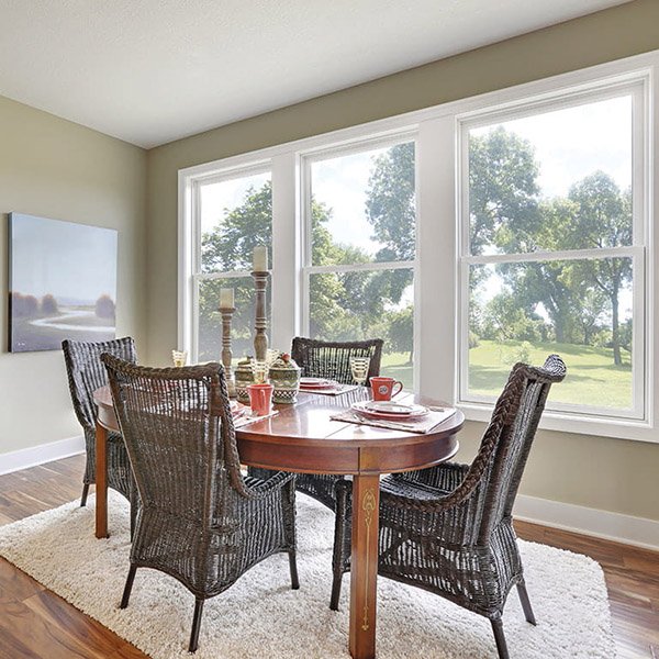 Room with dinning room table and chairs and three windows on the wall behind the table