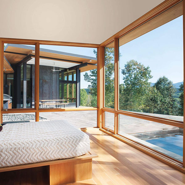 Bedroom with large windows on the walls from top to bottom looking out to an outdoor space with a pool, pavers, and an outdoor kitchen area