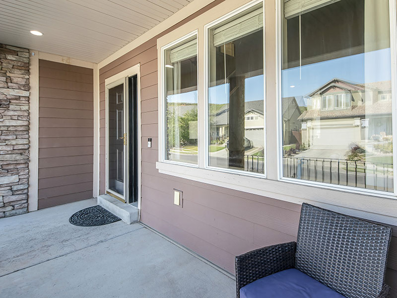 Side view of a front porch with pink-ish siding, three windows, and a front door to the left of the windows